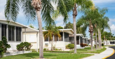 a row of nice mobile homes with palm trees out front